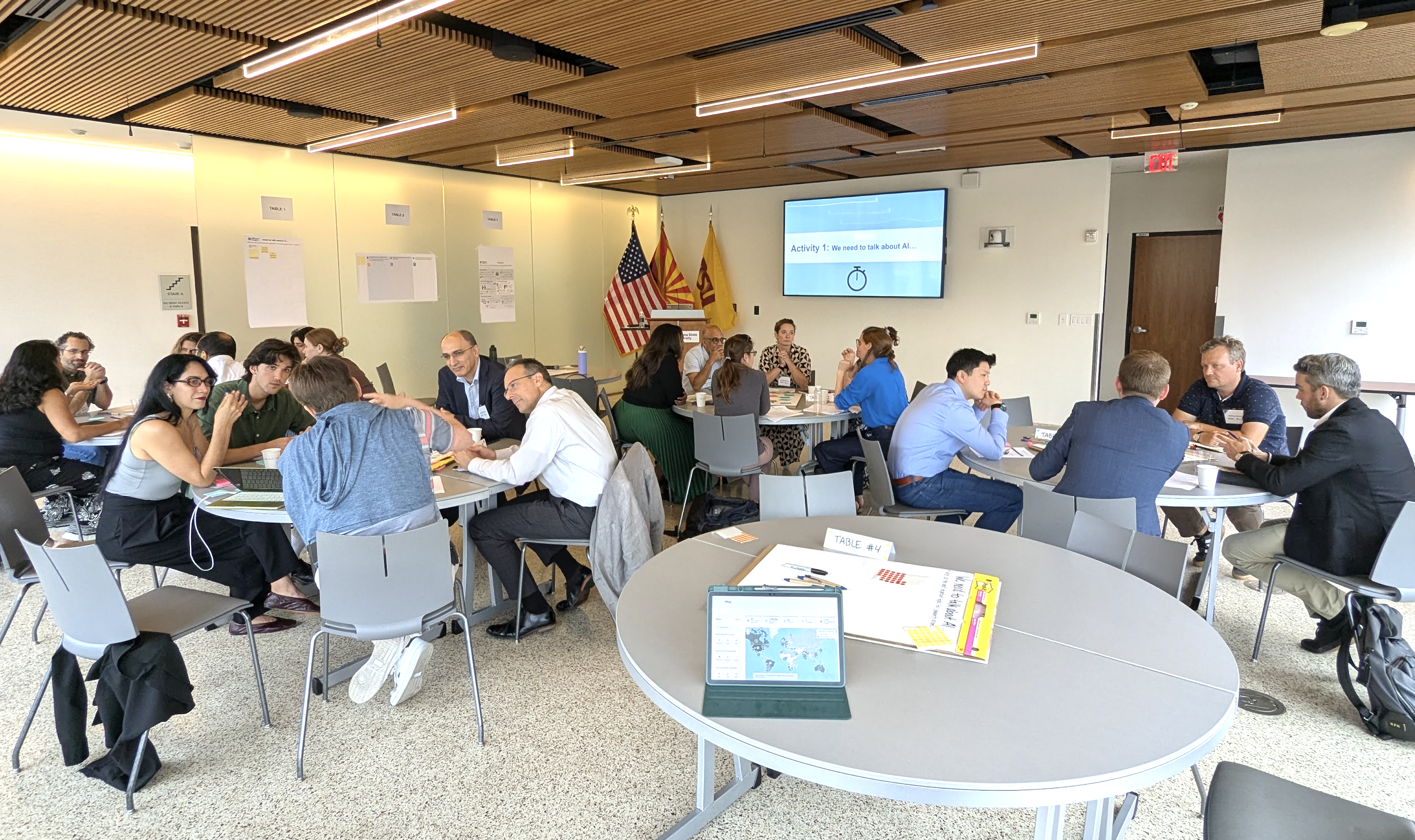 Image of workshop room with three round tables of participants